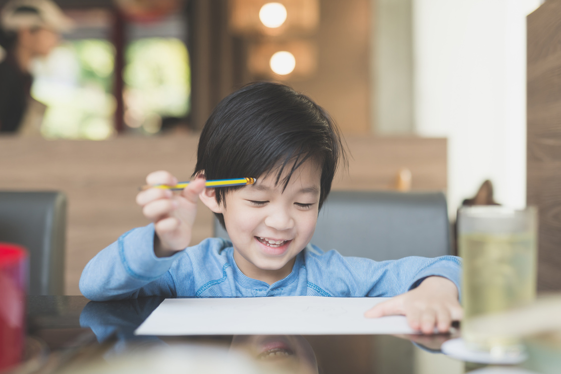 Asian child writing on white paper